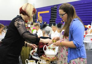 Student Ambassador Tori Lahney (R) helps University Village Activities Director Jayne Austin (L) make tea for the University Village table during the seventh annual Hats and High Tea event intended to raise money for scholarships on March 12 in Gilbert Arena. Photos by Amanda Souza- Staff Photographer 