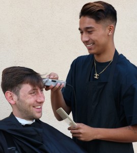 The hustle: “I’m busy all the time, it’s nice though, I like being busy,” Ugale said, cutting senior Brian McElroy’s hair. Photo by Inga Parkel - Photojournalist